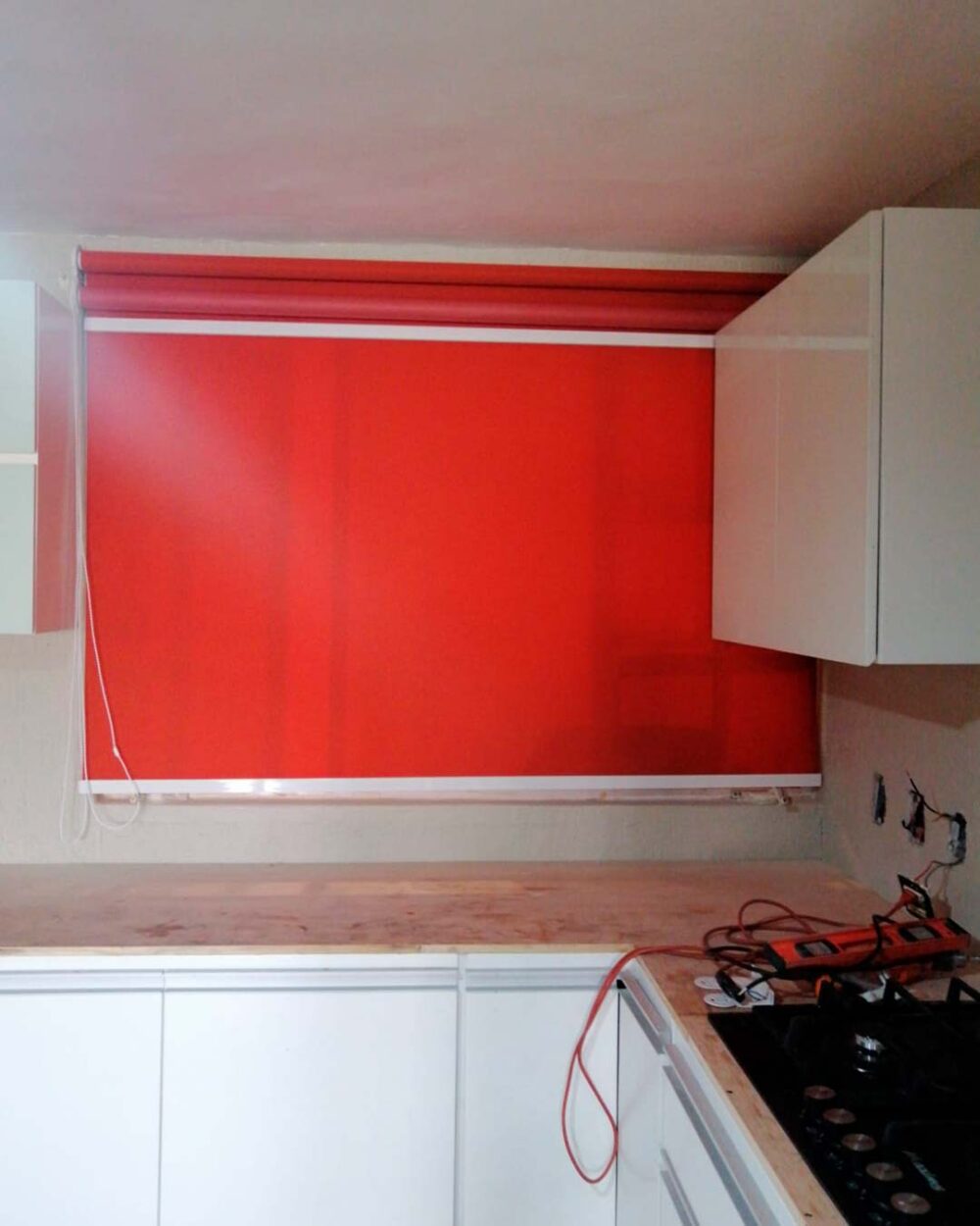 Persiana enrollable 0% visibilidad color rojo instalada en cocina moderna