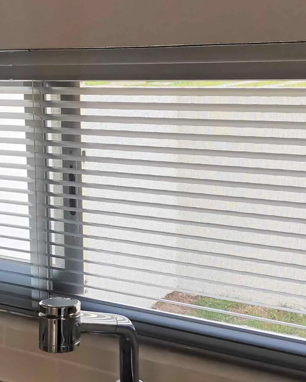 Persiana horizontal de aluminio instalada en ventana de cocina pequeña