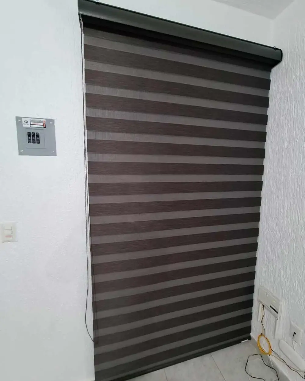 Vista vertical de persiana enrollable Sheer Elegance blackout en ventana amplia