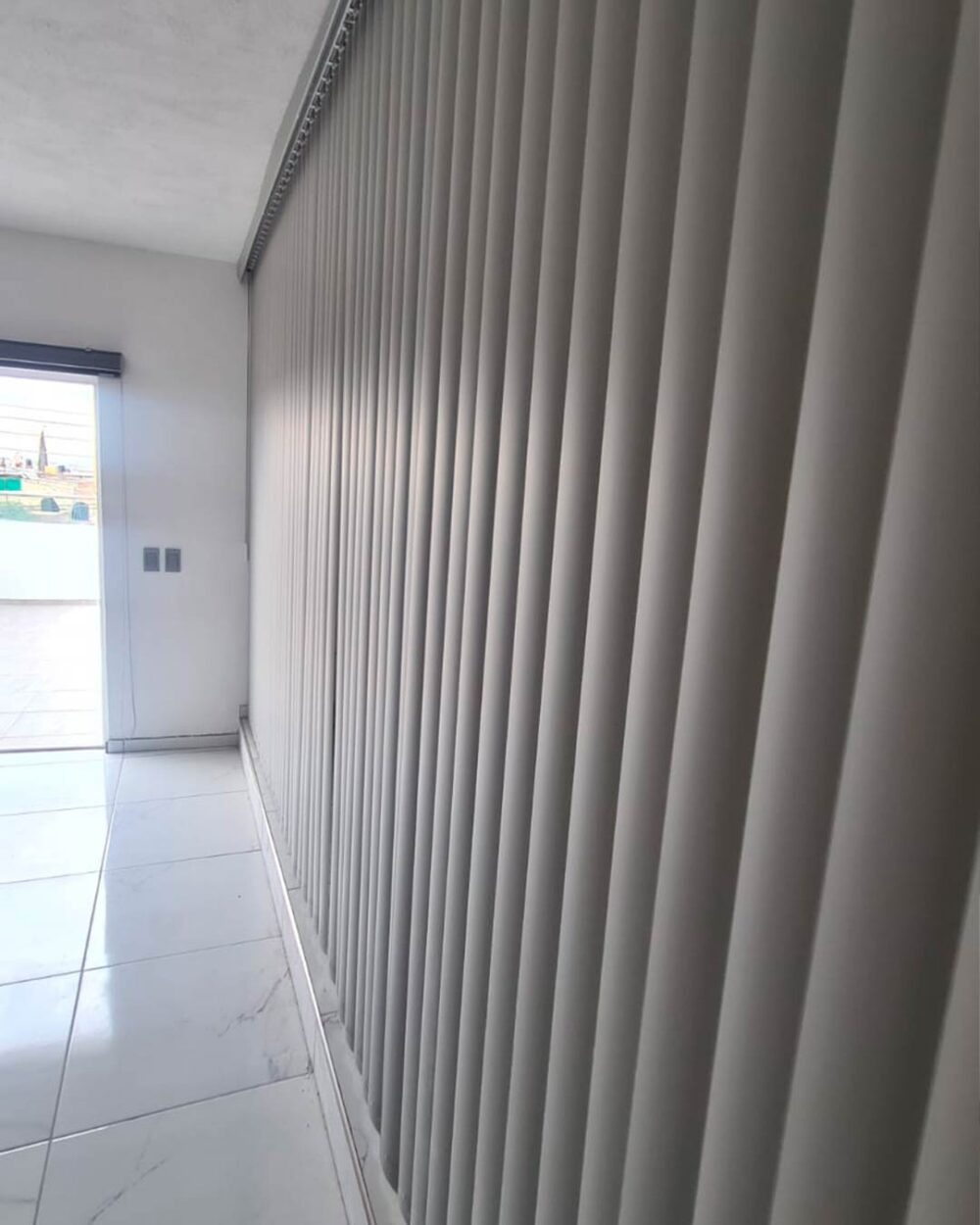 Persiana vertical de PVC vista lateral cubriendo ventana completa