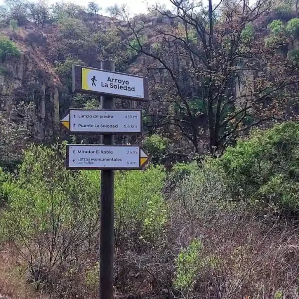 Poste de señalización en sendero La Soledad con direcciones hacia miradores y arroyos.