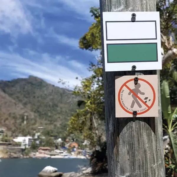 Poste con señal de sendero y prohibición de basura en playa de Quimixto, Jalisco.